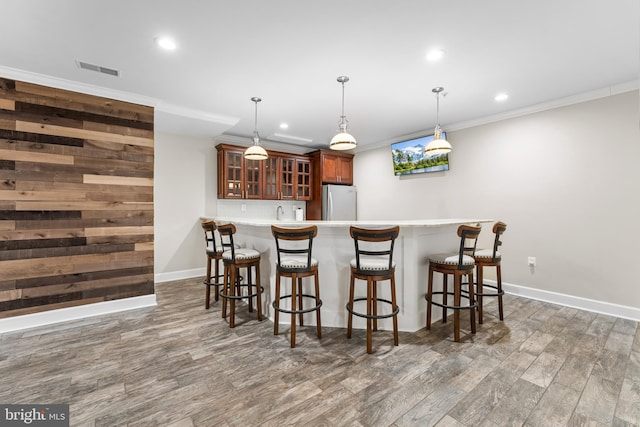 kitchen featuring kitchen peninsula, stainless steel fridge, hanging light fixtures, backsplash, and ornamental molding