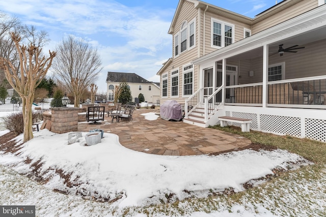 yard covered in snow with ceiling fan, a patio area, and a sunroom