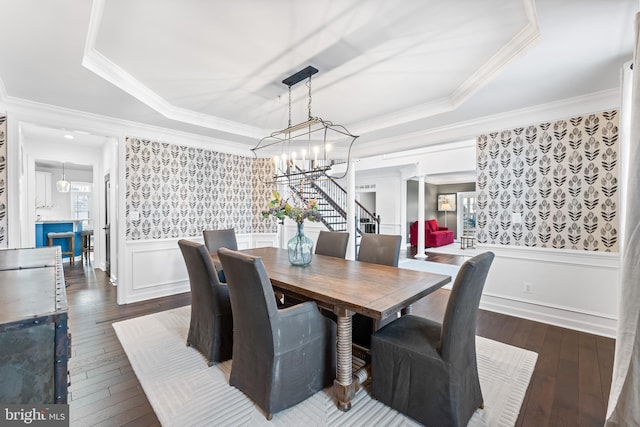 dining room featuring a notable chandelier, ornamental molding, dark wood-type flooring, and a tray ceiling