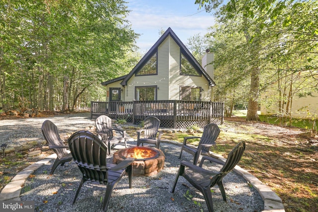 back of property featuring a wooden deck and an outdoor fire pit