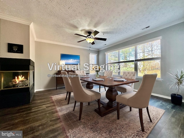 dining area with crown molding, a multi sided fireplace, dark hardwood / wood-style floors, and a textured ceiling