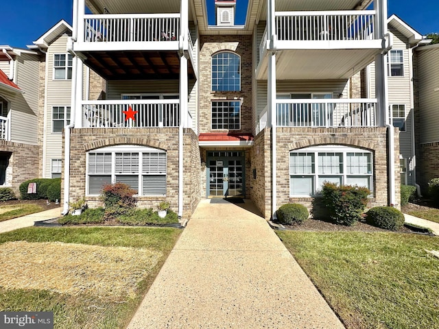 view of front of property featuring a front lawn and a balcony