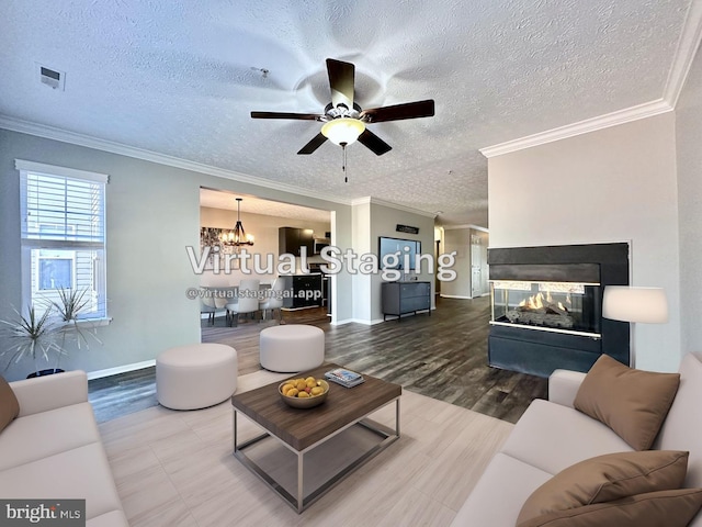 living room with crown molding, hardwood / wood-style floors, a multi sided fireplace, a textured ceiling, and ceiling fan with notable chandelier