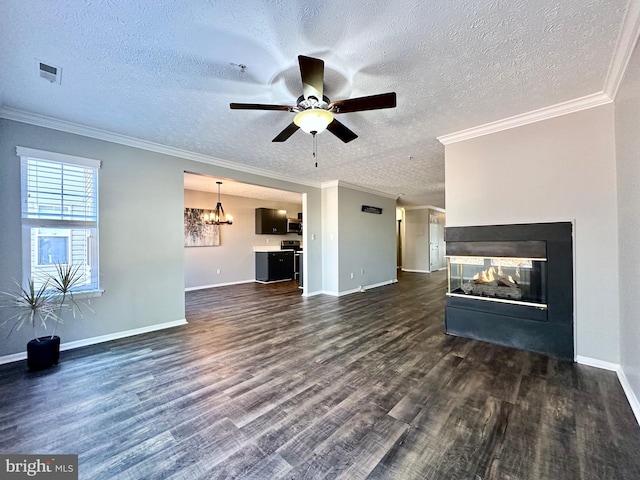 unfurnished living room with a multi sided fireplace, dark hardwood / wood-style floors, ceiling fan with notable chandelier, crown molding, and a textured ceiling