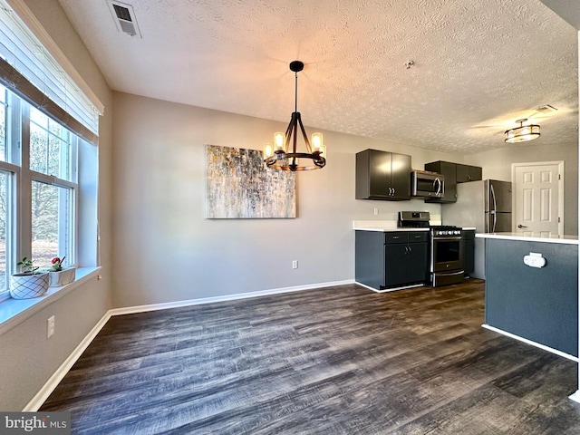 kitchen featuring appliances with stainless steel finishes, dark hardwood / wood-style floors, pendant lighting, an inviting chandelier, and a textured ceiling