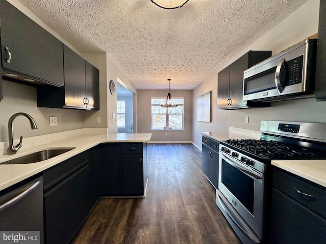 kitchen featuring appliances with stainless steel finishes, decorative light fixtures, sink, dark hardwood / wood-style flooring, and kitchen peninsula