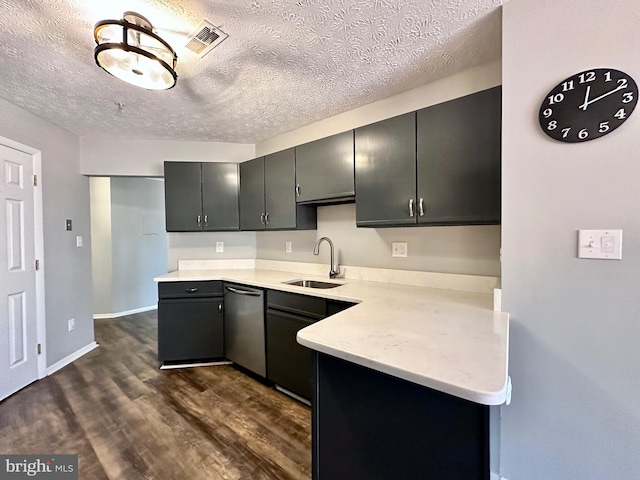 kitchen featuring dark hardwood / wood-style floors, dishwasher, sink, kitchen peninsula, and a textured ceiling