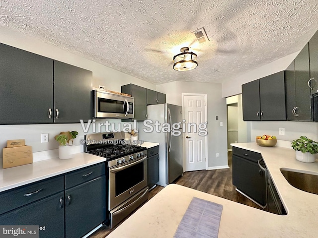 kitchen featuring stainless steel appliances, dark hardwood / wood-style floors, and a textured ceiling