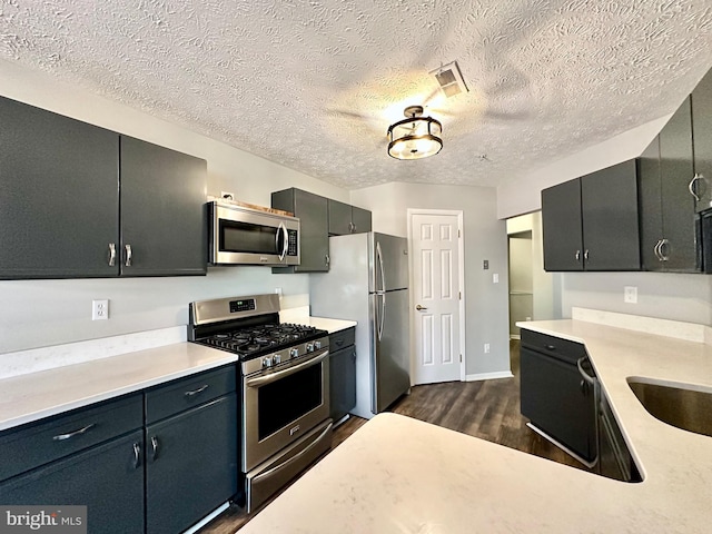 kitchen featuring dark wood-type flooring, stainless steel appliances, sink, and a textured ceiling