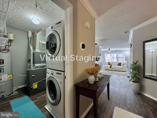 laundry area with crown molding, dark wood-type flooring, water heater, stacked washing maching and dryer, and a textured ceiling