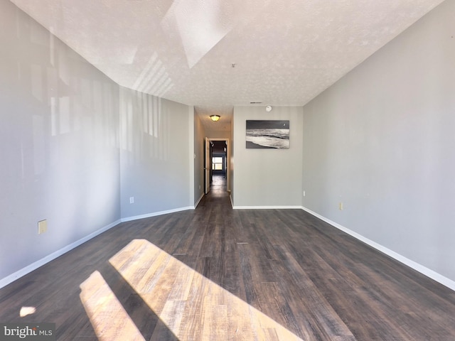 unfurnished room with dark hardwood / wood-style floors and a textured ceiling