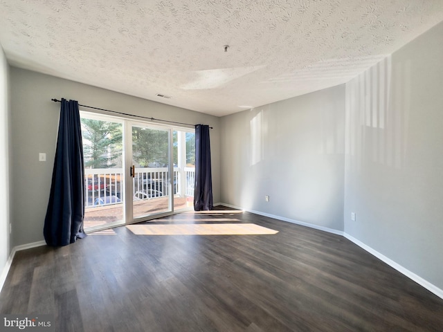 empty room with dark wood-type flooring and a textured ceiling