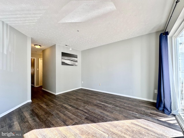 empty room with a textured ceiling and dark hardwood / wood-style flooring