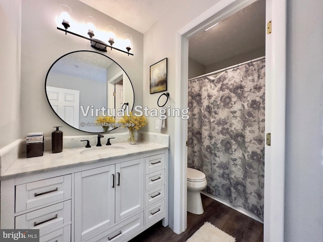 bathroom with vanity, toilet, hardwood / wood-style floors, and a textured ceiling