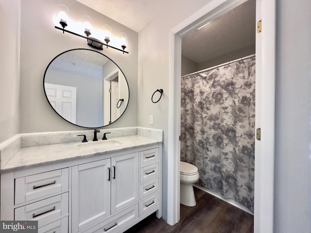 bathroom with vanity, wood-type flooring, a textured ceiling, curtained shower, and toilet