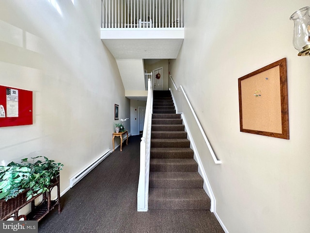 stairs featuring a baseboard radiator and a high ceiling