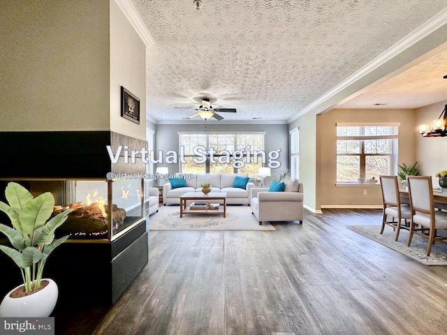 living room featuring dark hardwood / wood-style flooring, crown molding, ceiling fan with notable chandelier, and a textured ceiling