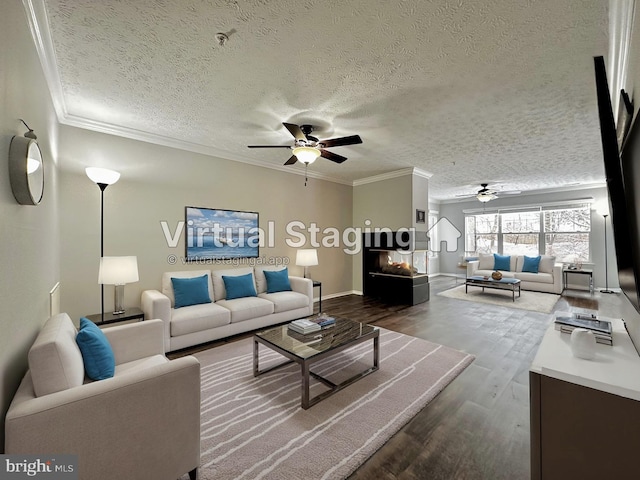 living room featuring ceiling fan, ornamental molding, wood-type flooring, and a textured ceiling