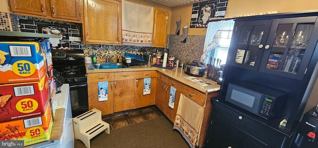 kitchen featuring decorative backsplash, black appliances, and sink