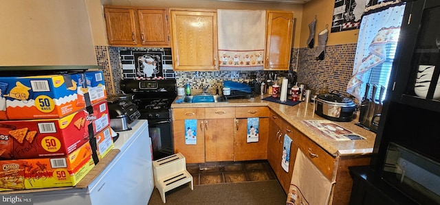 kitchen featuring black gas range oven, tasteful backsplash, fridge, and sink