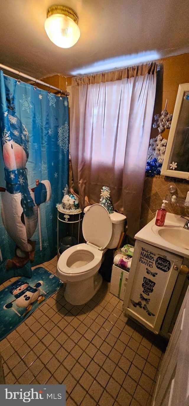 bathroom featuring toilet, a shower with shower curtain, tile patterned flooring, and sink