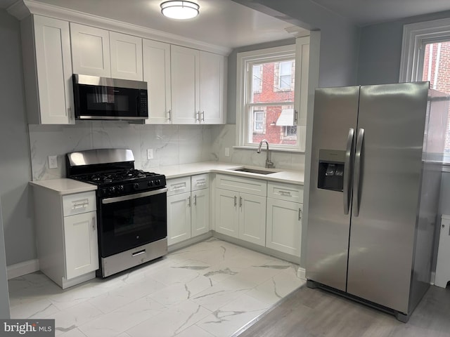 kitchen with tasteful backsplash, sink, stainless steel appliances, and white cabinetry