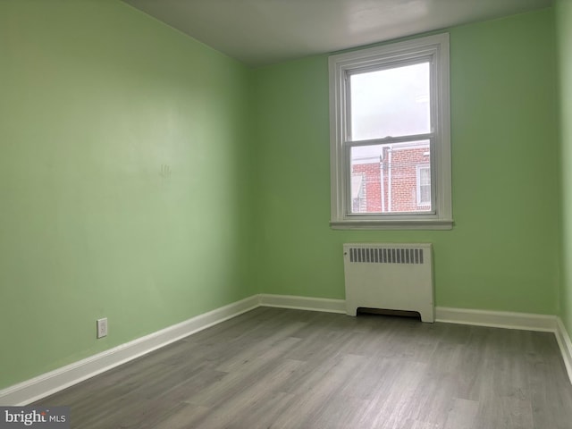 unfurnished room featuring radiator heating unit and light hardwood / wood-style floors