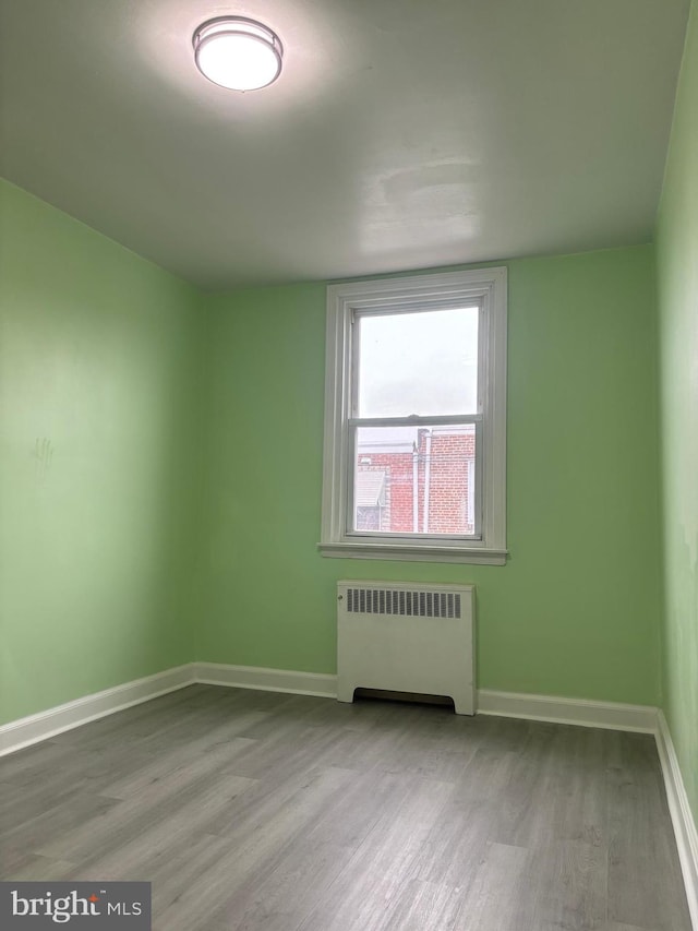 empty room with radiator heating unit and light hardwood / wood-style flooring