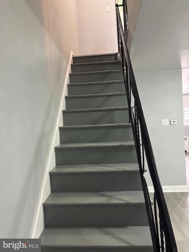 stairs featuring radiator heating unit and hardwood / wood-style flooring