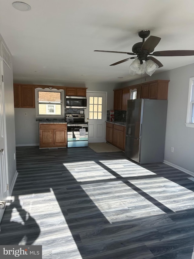 kitchen with ceiling fan, stainless steel appliances, dark hardwood / wood-style flooring, and tasteful backsplash