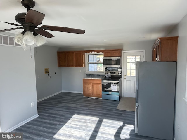 kitchen with ceiling fan, backsplash, appliances with stainless steel finishes, and dark hardwood / wood-style floors