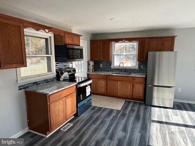 kitchen with tasteful backsplash, sink, light stone countertops, appliances with stainless steel finishes, and dark hardwood / wood-style flooring