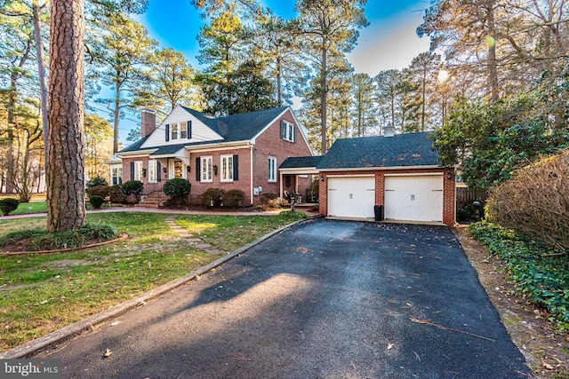 cape cod house with a garage and a front lawn