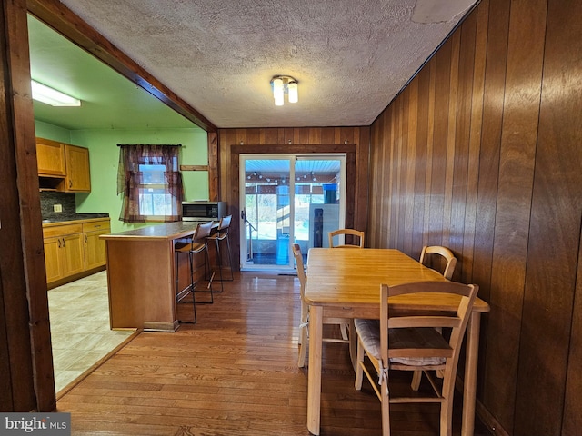 dining area with wooden walls and light hardwood / wood-style floors