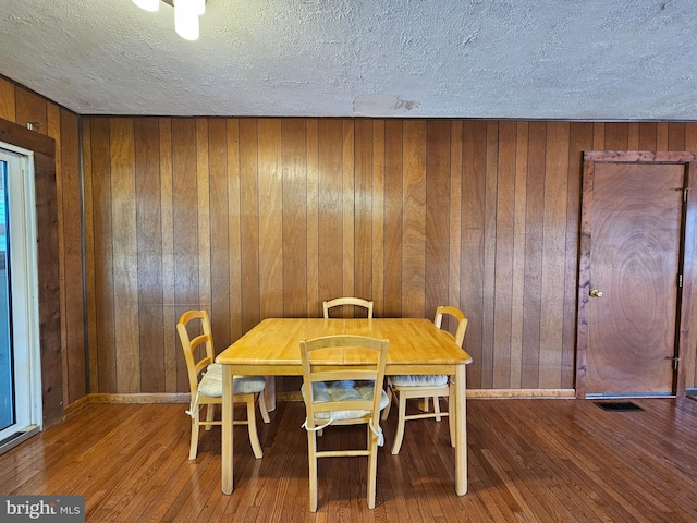 dining space featuring hardwood / wood-style floors and wood walls