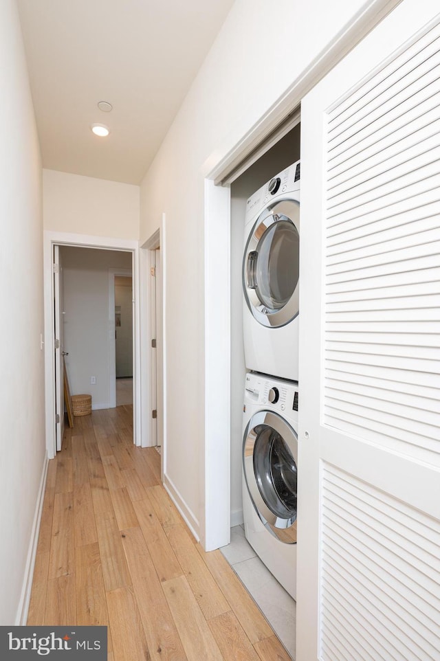 washroom with stacked washer and dryer and light hardwood / wood-style flooring