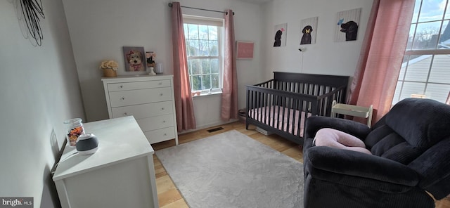 bedroom featuring light wood-type flooring and a crib