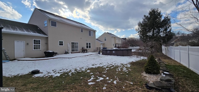 snow covered back of property featuring a fenced in pool