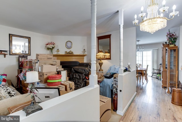 living room featuring a notable chandelier, light wood-type flooring, and decorative columns