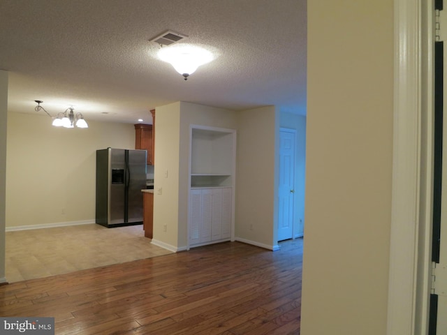 kitchen with baseboards, visible vents, stainless steel fridge with ice dispenser, a textured ceiling, and light wood-type flooring