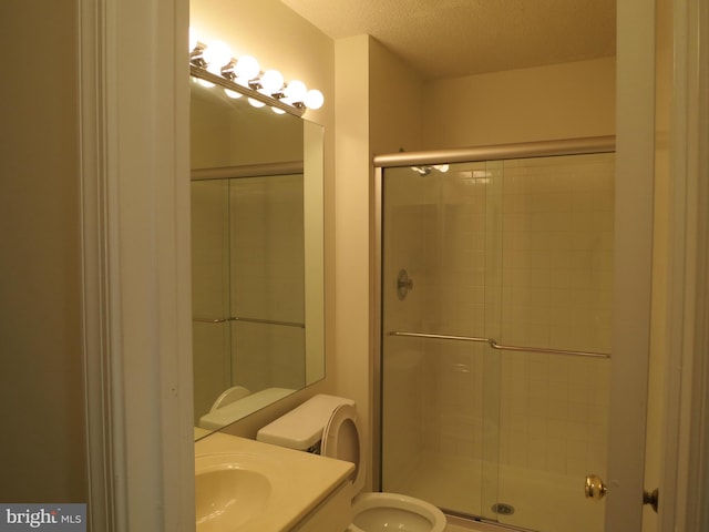 bathroom with toilet, a stall shower, a textured ceiling, and vanity