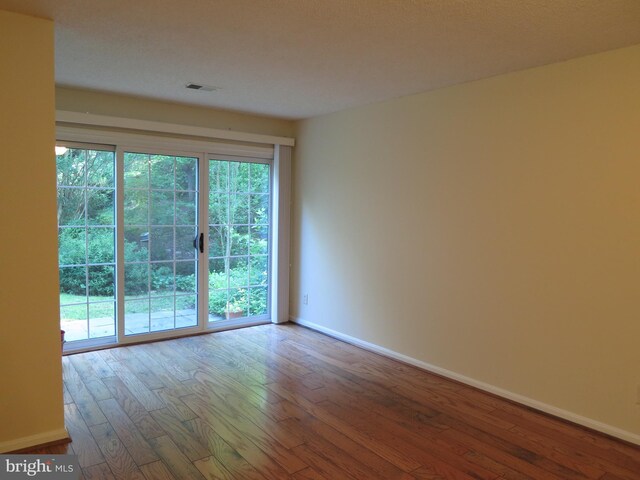 spare room with baseboards and hardwood / wood-style flooring