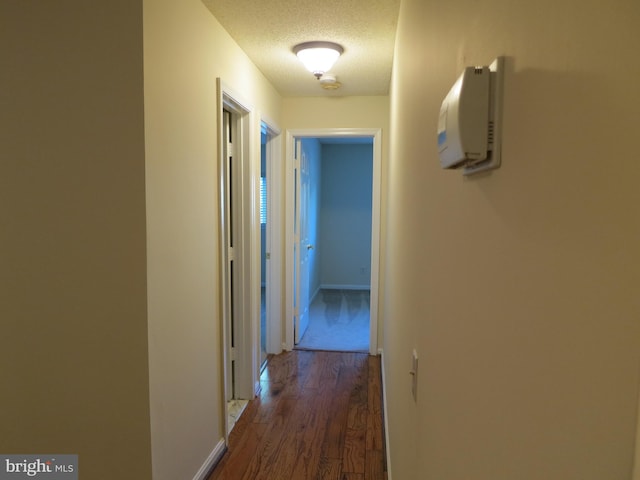 corridor with dark wood-type flooring and a textured ceiling