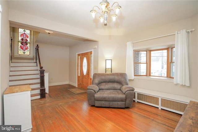 living area with an inviting chandelier, a healthy amount of sunlight, wood-type flooring, and radiator heating unit