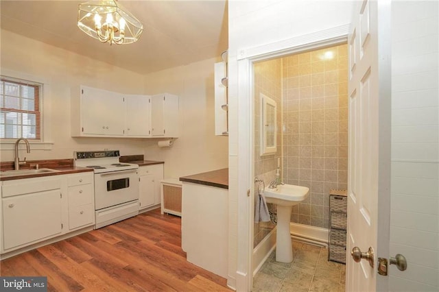 kitchen featuring white cabinets, white electric range oven, sink, hanging light fixtures, and a chandelier