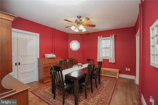 dining space with ceiling fan, radiator heating unit, and hardwood / wood-style flooring