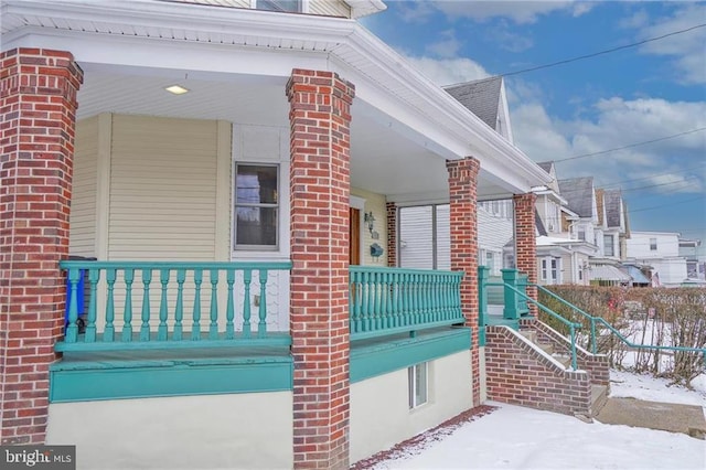 view of snowy exterior with covered porch