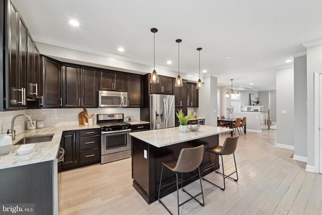 kitchen featuring stainless steel appliances, a center island, hanging light fixtures, and sink