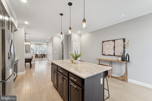 kitchen with stainless steel refrigerator with ice dispenser, pendant lighting, crown molding, light hardwood / wood-style flooring, and dark brown cabinetry