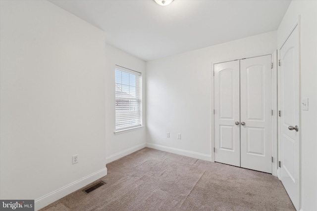 unfurnished bedroom featuring light carpet and a closet